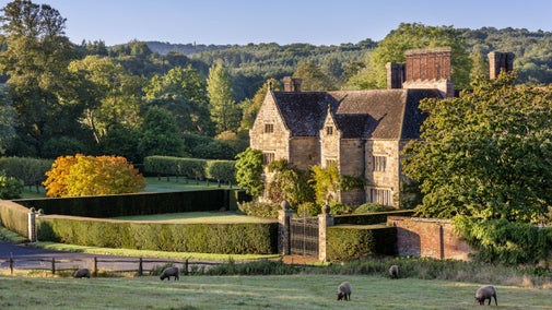 The east front of the house at Bateman's, East Sussex in autumn with sheep in the foreground